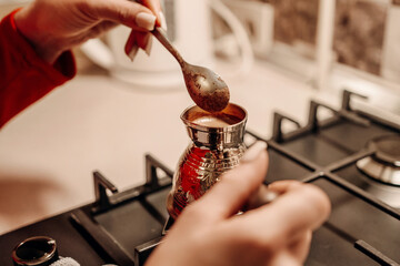Coffee Preparation Kitchen Stovetop Brewing: Woman adds sugar to Turkish coffee pot on gas stove.