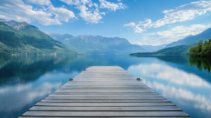 Obraz premium A scenic wooden pier extending into a serene lake, surrounded by mountains, with a clear summer sky and calm waters reflecting the beauty of nature