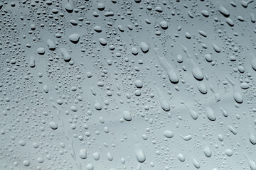 Water drops on grey glass surface, closeup