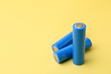 Three AA cell batteries on yellow background, closeup. Space for text