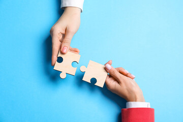 Business strategy and teamwork concept. Partners putting puzzle pieces together on light blue...