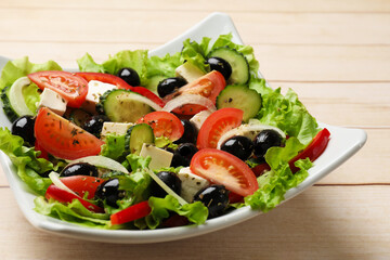 Delicious fresh Greek salad on white wooden table, closeup