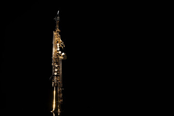 Jazz. One saxophone on mirror surface against black background, space for text