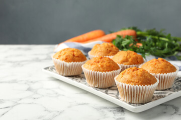 Tasty carrot muffins and fresh vegetables on white marble table, closeup. Space for text