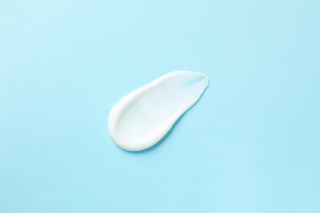 Sample of body cream on light blue background, top view