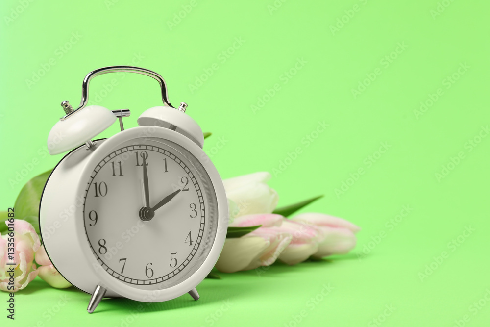 Poster spring time. alarm clock and beautiful tulips on green background, space for text