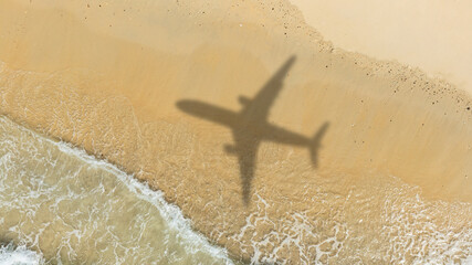 Aerial view of shadow passenger plane silhouette and sandy beach blue sea with waves at sea beach summer vacation sea travel concept	
