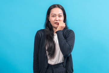 Asian woman with long black hair wearing a black cardigan and white shirt, biting her nails with a...