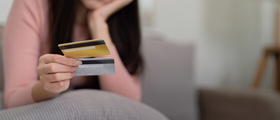 Credit Management and Financial Habit. A woman holds credit cards while evaluating her financial options, illustrating financial literacy.