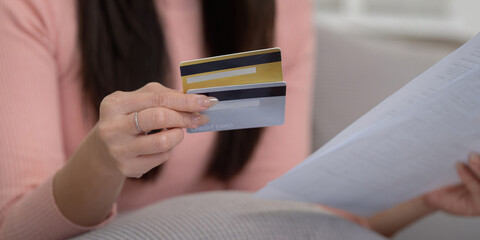 Credit Management and Finance Strategy. Close-up of a woman holding multiple credit cards and reviewing paperwork as part of her financial strategy.
