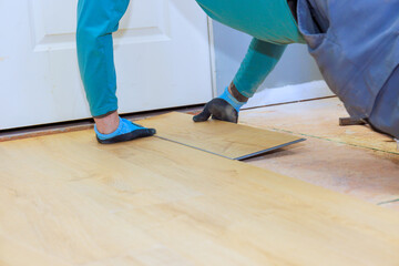 Carpenter carefully lays down laminate flooring in room during home renovation