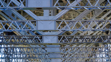 Detailed view of intricate steel lattice structure beneath a major bridge showcasing engineering excellence and design precision