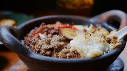 Gudeg porridge topped with shredded chicken, pindang eggs, tofu, krecek and jackfruit on a clay pot. Gudeg is a traditional cuisine from Jogja. 