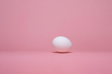 A single egg placed on a soft pink background, symbolizing freshness and natural nutrition.
