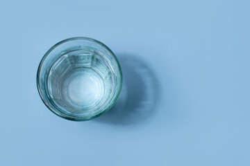 A glass of water placed on a light blue background, symbolizing hydration, freshness, and purity.