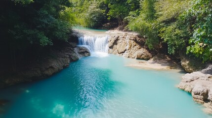Fototapeta premium Lush turquoise waterfall cascading into a pool surrounded by dense jungle