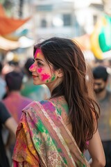 A candid shot of a woman in a traditional saree walking through a festival street, her face partially covered in Holi colors