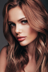 Fototapeta premium Fashion beauty portrait of young brunette woman with evening stylish makeup and perfect clean skin. Sexy model with curly hairstyle posing in studio. With bright natural lips