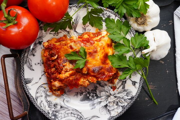 Cooking homemade lasagna from scratch. Using noodles, pasta sauce, ricotta, mozzarella cheese and Italian herbs. Boiling the noodles, browning the ground beef and layering the lasagna for a meal.