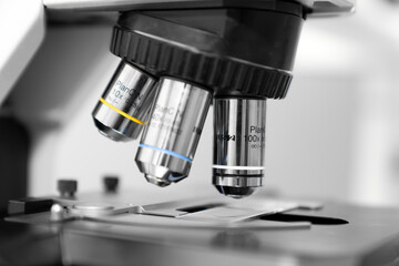 Close up of a high-precision laboratory microscope with 10x, 40x, and 100x objective lenses, used for scientific research, medical diagnostics, biotechnology, and microbiology analysis in a profession