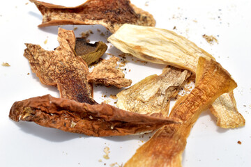 Pieces of porcini mushrooms, sliced ​​and dried, lie on a white background