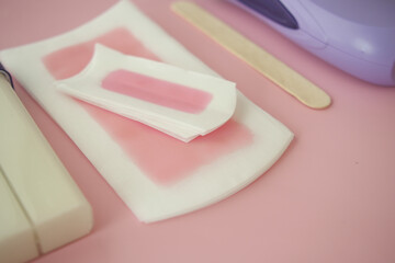 Waxing supplies arranged on a pink surface for personal care