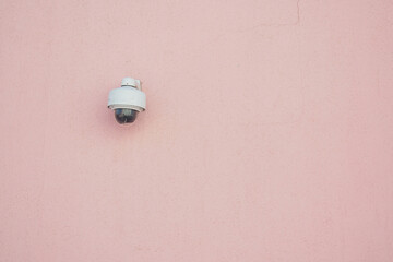 Security camera mounted on pink wall enhances safety in location