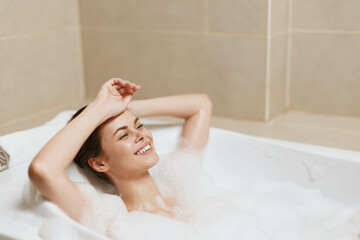 Relaxed woman enjoying a bubble bath, smiling blissfully and soaking in the soothing warmth of the water. Self-care and wellness concept for tranquility and relaxation.