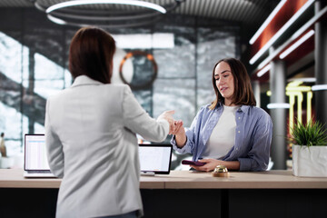 Hotel receptionist greets woman checking in