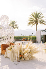 Bouquet of cortaderia stands near a set table near a wire sculpture