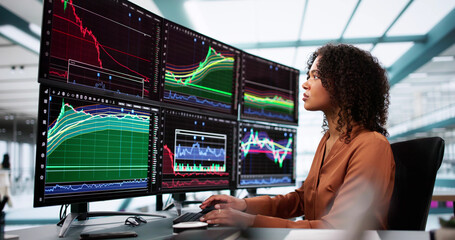 Stock Market Broker Looking At Graphs On Multiple Screens