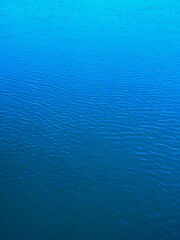 橋の上から見る川の水面の青いグラデーション