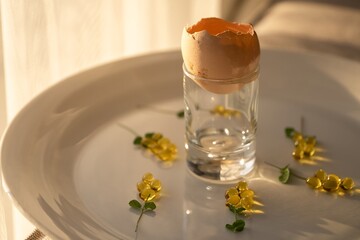 Cracked Eggshell with Raw Yolk in a Glass, Surrounded by Supplements