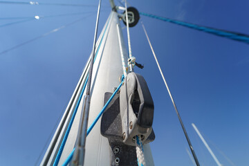 Tall sturdy mast of a sailboat stands out vividly against the bright blue sky.