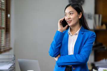 Attractive Asian businesswoman in the office is talking while calling a customer on a mobile phone.