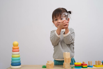 A young child playing with toys, stacking colorful blocks and exploring a transparent ball,...