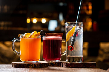 Three crafted cocktails on rustic coasters showcase unique flavors and garnishes