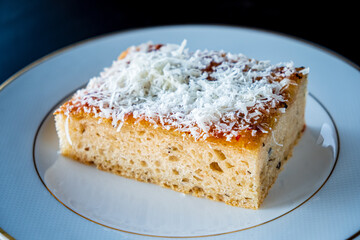 A slice of moist baked dessert showcases a golden crust with a sprinkle of cheese on top