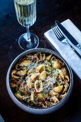 A tasty pasta bowl with rich sauce and cheese, paired with a drink in a cozy spot