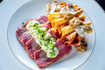 Savory beef slices topped with herb sauce, served alongside pasta drizzled in creamy mushroom sauce