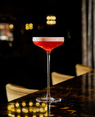 A stunning cocktail with vibrant red hues stands tall on a polished table in a chic venue