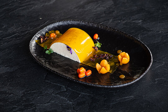 A beautifully crafted dessert with bright yellow elements, delicate flowers, and vibrant garnishes