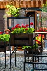 Elevated planters overflow with bright red and green plants, enhancing the charming outdoor setting