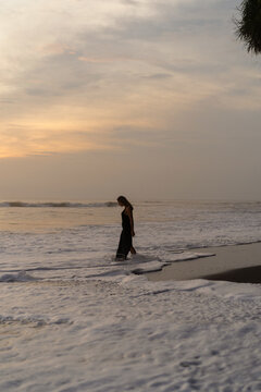 Beautiful woman in long dress on the beach at sunset. Bali