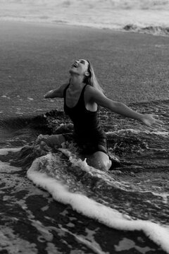 Beautiful woman in the foam of the waves on the beach at sunset. Bali
