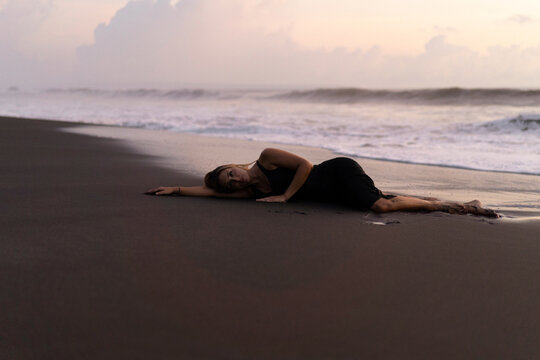 Beautiful woman lying on the sand on the beach at sunset. Bali
