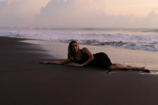 Beautiful woman lying on the sand on the beach at sunset. Bali