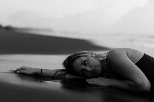 Beautiful woman lying on the sand on the beach at sunset. Bali