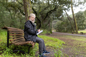 Fototapeta premium Senior writer taking notes in peaceful park setting