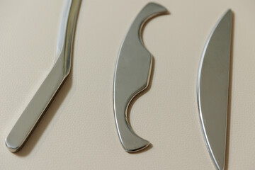 Intelligent stainless steel IASTM instruments for soft tissue massage and pain relief, the instruments lie on a beige massage table